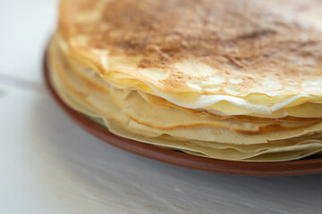 Crepes, thin pancakes on a plate on a white wooden table