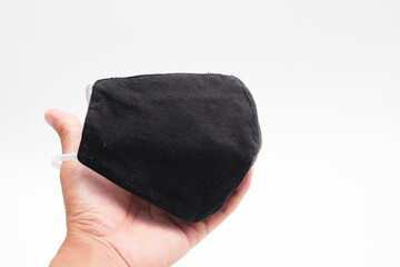 Reusable black cloth mask with white strap on hand for preventing Covid-19 spreads isolated on white background.