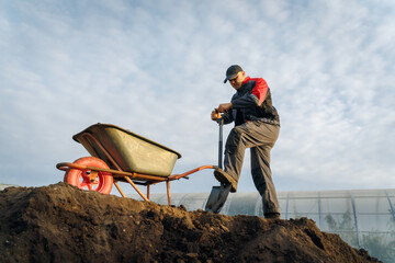 Working with garden tools, shovel and wheelbarrow on the site of a country house. Preparation for construction work.