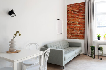 Industrial interior of living room in hotel. Stylish room in apartment with sofa and table with chairs. Trendy design.