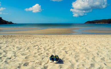 Fototapeta na wymiar Dos zapatillas de deporte en la arena de una playa desierta de Galicia