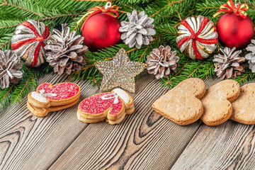 festive christmas and new year background with copy space, fir branches, Christmas decorations, pine cones and gingerbread cookies on a vintage wooden table
