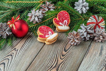 festive christmas and new year background with copy space, fir branches, Christmas decorations, pine cones and gingerbread cookies on a vintage wooden table