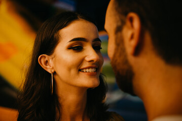A girl and a boy are walking holding each other's hands between amusement rides
