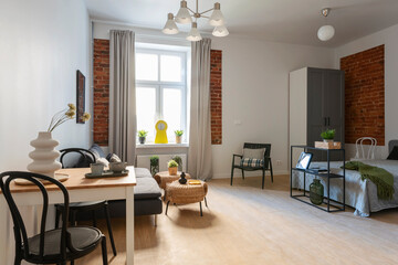 Room interior with stylish space and window. Cozy living room with sofa, table and modern chair in spacious apartment at home. Hotel.