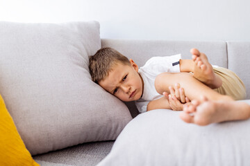 Obraz na płótnie Canvas Cute angry boy. Morning home. Naughty little boy. Angry little boy frowned while sitting in bed and looking at camera. Angry boy with furrowed brows. Offended boy sitting on sofa