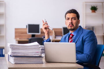 Young male employee unhappy with excessive work at workplace