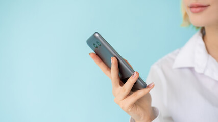 Business message. Office woman. Mobile communication. Advertising background. Unrecognizable lady holding smartphone isolated blue copy space.