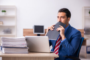 Young male employee unhappy with excessive work at workplace