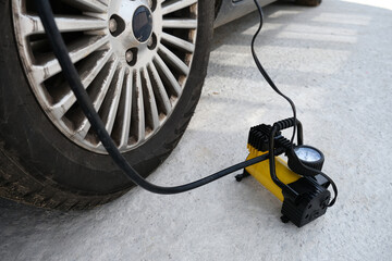 The deflated car wheel is inflated by an electric compressor, car accident concept