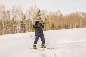 a hunter or poacher stands on skis at the edge of the forest and aims an automatic weapon at prey...