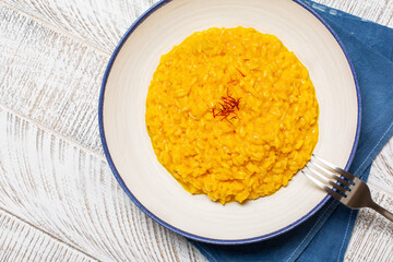 Risotto allo Zafferano. Italian dish made from saffron, rice and vegetable bouillon. Close-up, top view.