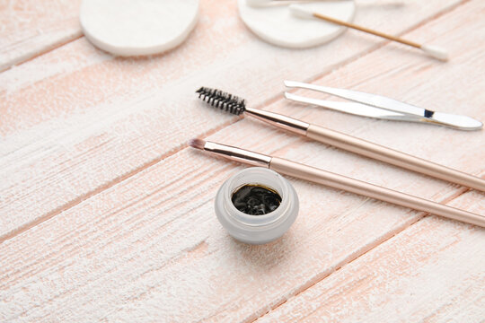 Henna and tools for eyebrows correction on color wooden background, closeup