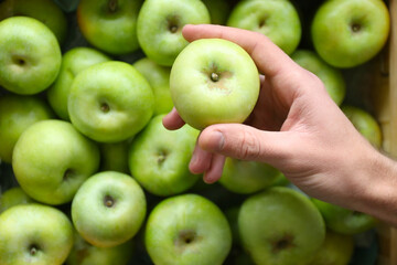 Young man choosing apples in market