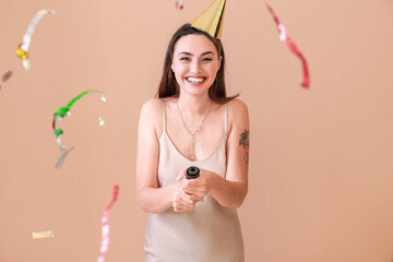 Happy woman with party popper on color background