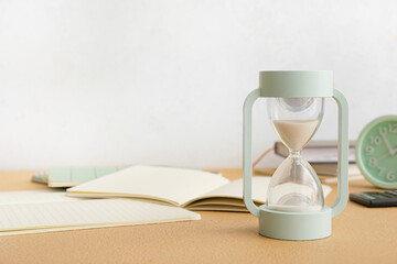 Stylish hourglass on light table. Deadline concept