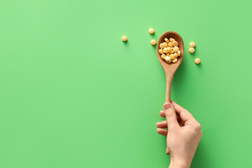 Female hand and spoon with pills on color background