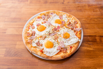 Pizza with four fried eggs with yellow yolks for dipping bread with pieces of ham and chicken with oregano