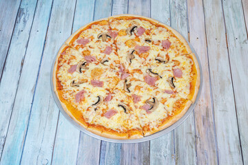 Prosciutto pizza with mushrooms and lots of melted mozzarella cheese sliced into portions with foil tray