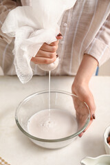 Fototapeta na wymiar Woman preparing tasty hazelnut milk on kitchen table, closeup
