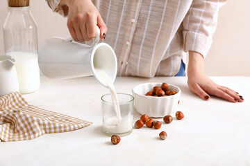 Obraz na płótnie Canvas Woman preparing tasty hazelnut milk on kitchen table, closeup