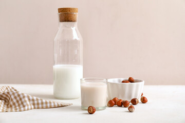 Glass of tasty hazelnut milk and ingredients on kitchen table