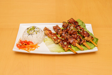 Charcoal-grilled pork skewers with lettuce and barbecue sauce with vegetables and white rice with poppy seeds