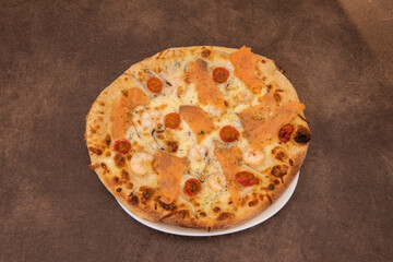 Italian pizza di mare with cooked prawns, cherry tomatoes and smoked salmon with dill and mozzarella cheese