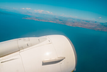 View from jet to paradise islands in ocean. Camera filming from aircraft porthole. Earth landscape and sea through window.