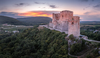 Fototapeta na wymiar Aerial view of ruined Gothic Csesznek castle in the Bakony region of Hungary in Veszprem county with old palace building, gate tower with colorful dramatic sunset
