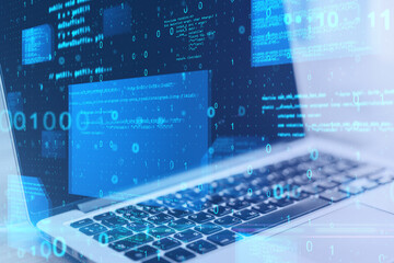 Close up of laptop at desktop with abstract glowing blue coding background. Binary code, technology, data and internet concept. Double exposure.