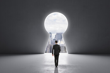 Back view of businessman walking in concrete interior with abstract keyhole window with city view....