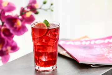 Glass of tasty ice tea with lime on table in room