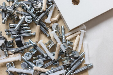 Opened box with furniture assembly parts and tools on the floor. Self assembling and DIY furniture at home concept. Bolts and screws closeup