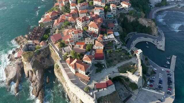 Ulcinj Montenegro old town on the Mediterranean sea coast is popular tourist destination, medieval stone houses with red roofs built on rocky promontory. Drone aerial view of the sunny cityscape.