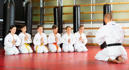 Coach in kimono tanding and greeting his students before lesson in the gym