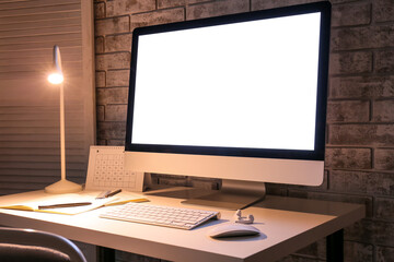 Fototapeta premium Stylish workplace with modern computer and lamp in evening