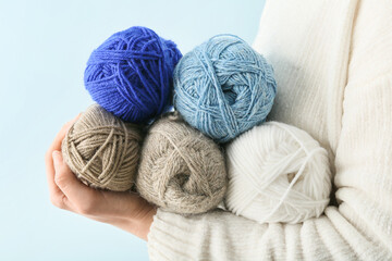 Woman holding knitting yarn on color background, closeup