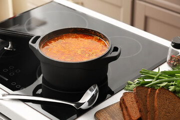 Cooking pot with delicious borscht on stove in kitchen