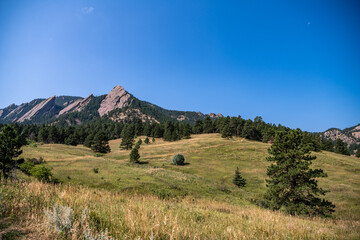 Fototapeta premium Beautiful scenery at the Chautauqua Park Hiking area. The famous flatirons rock formation is visible. Top of the rocky mountain is in focus.