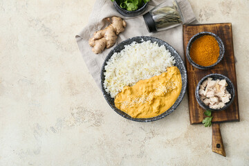 Bowl of tasty chicken curry with rice and ingredients on light background