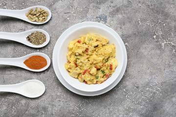 Bowl of tasty chicken curry and different spices on grunge background