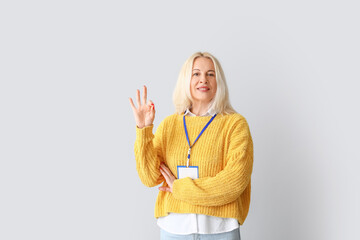 Portrait of mature woman with badge showing OK on grey background