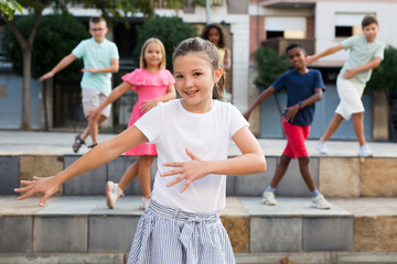 Young boys and girls dancing outdoors. They're performing street dance moves and having fun.