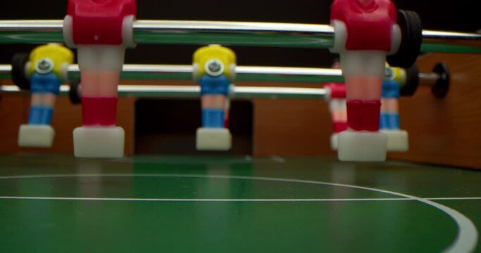Close-up of friends playing table football close-up. Slow motion. Shallow depth of field. Football match Football on the gaming table. Filming inside the playing field.