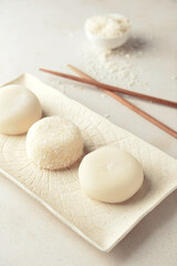 Tray with tasty Japanese mochi and chopsticks on light background