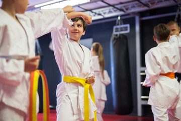 Focused preteen boys practicing new karate moves in pairs at sport gym