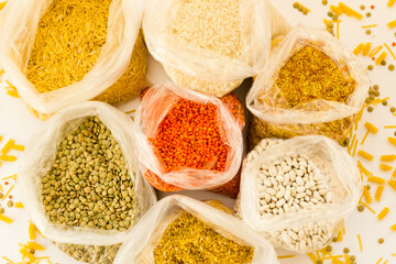 Uncooked dry cereal food group in nylon bags on white surface,above view