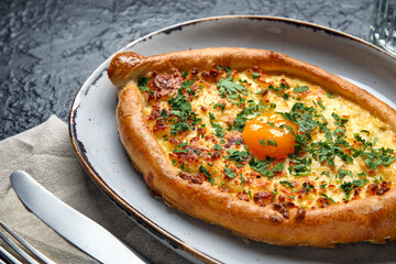 Plate with tasty Ajarian khachapuri on dark background, closeup