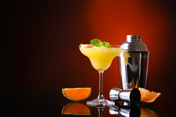 Glass of tasty orange margarita cocktail on dark color background